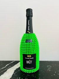 a bottle of champagne with green beads on it